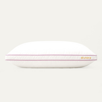 A white Alunara pillow with a thin magenta stripe along the edge and the brand name 'alunara' printed in gold on the side, set against a solid off-white background.